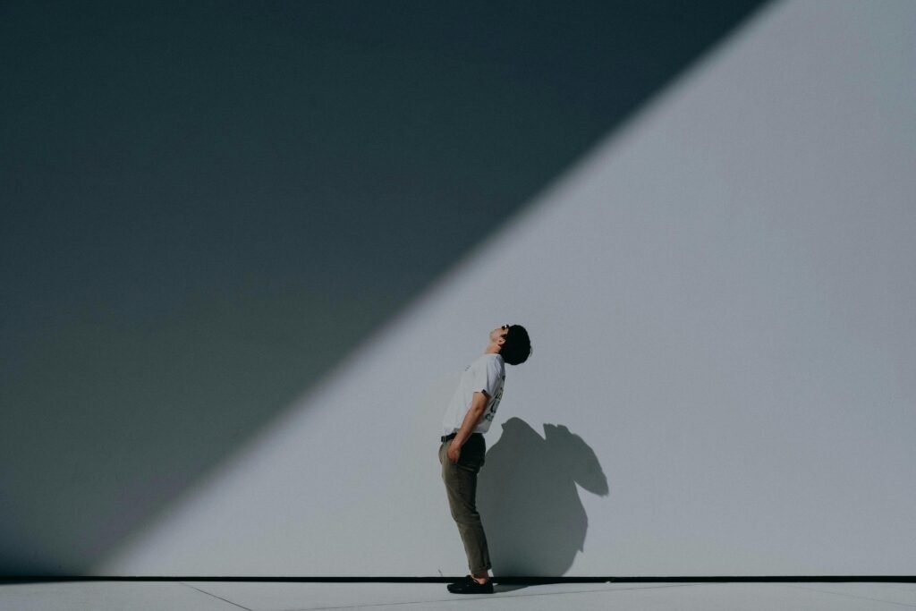 Ein Mann trägt ein weißes T-Shirt und weiße Shorts und steht entspannt an einer weißen Wand, minimalistisch und modern inszeniert.