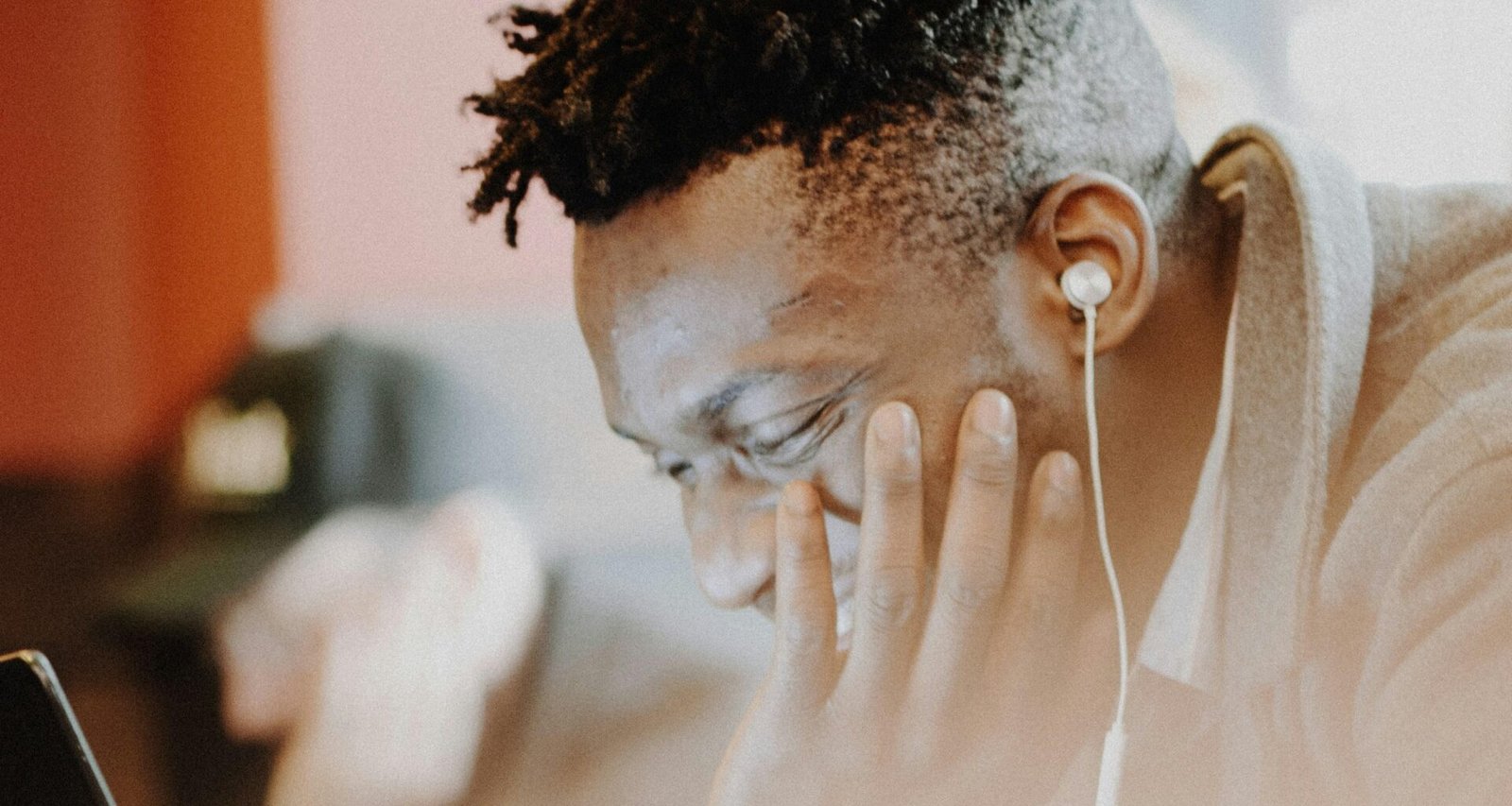 Mann mit Kopfhörern sitzt lachend vor einem Computerbildschirm in einem modernen Büro