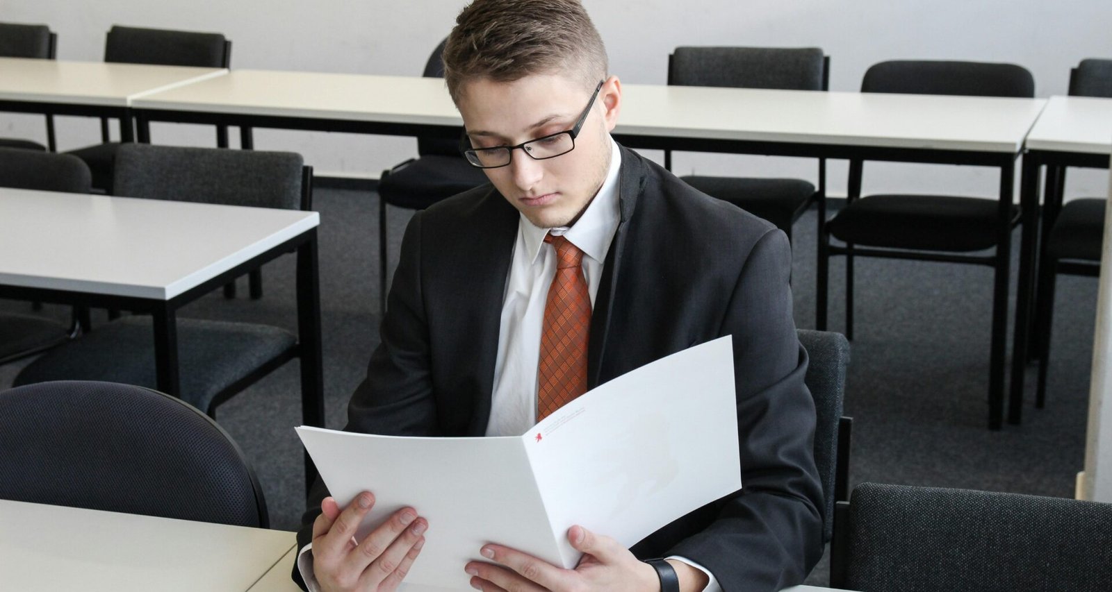 Ein Mann steht in einem leeren Raum und hält einen Ordner in den Händen, Fokus auf Raum und Dokumente.