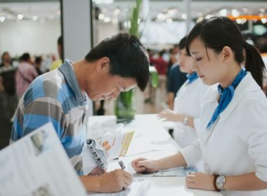 Ein Mann unterschreibt ein Dokument an einem Service-Counter, ideal zur Illustration von Vertragsabschlüssen und Serviceprozessen.