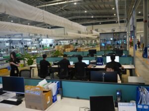 Menschen arbeiten gemeinsam an Computern in einem offenen, modern eingerichteten Büro mit technischen Arbeitsplätzen.