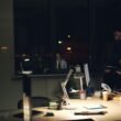 Personen arbeiten in einem gedimmten Büro bei Nacht an ihren Computern und sind auf Bildschirme fokussiert.