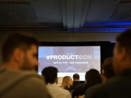 Mehrere Personen sitzen in einem Konferenzraum und verfolgen eine Präsentation auf einer Projektionsleinwand.