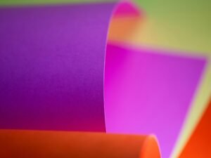 Detailaufnahme einer aufgerollten, farbigen Papierrolle mit verschiedenen Farbschichten im Fokus