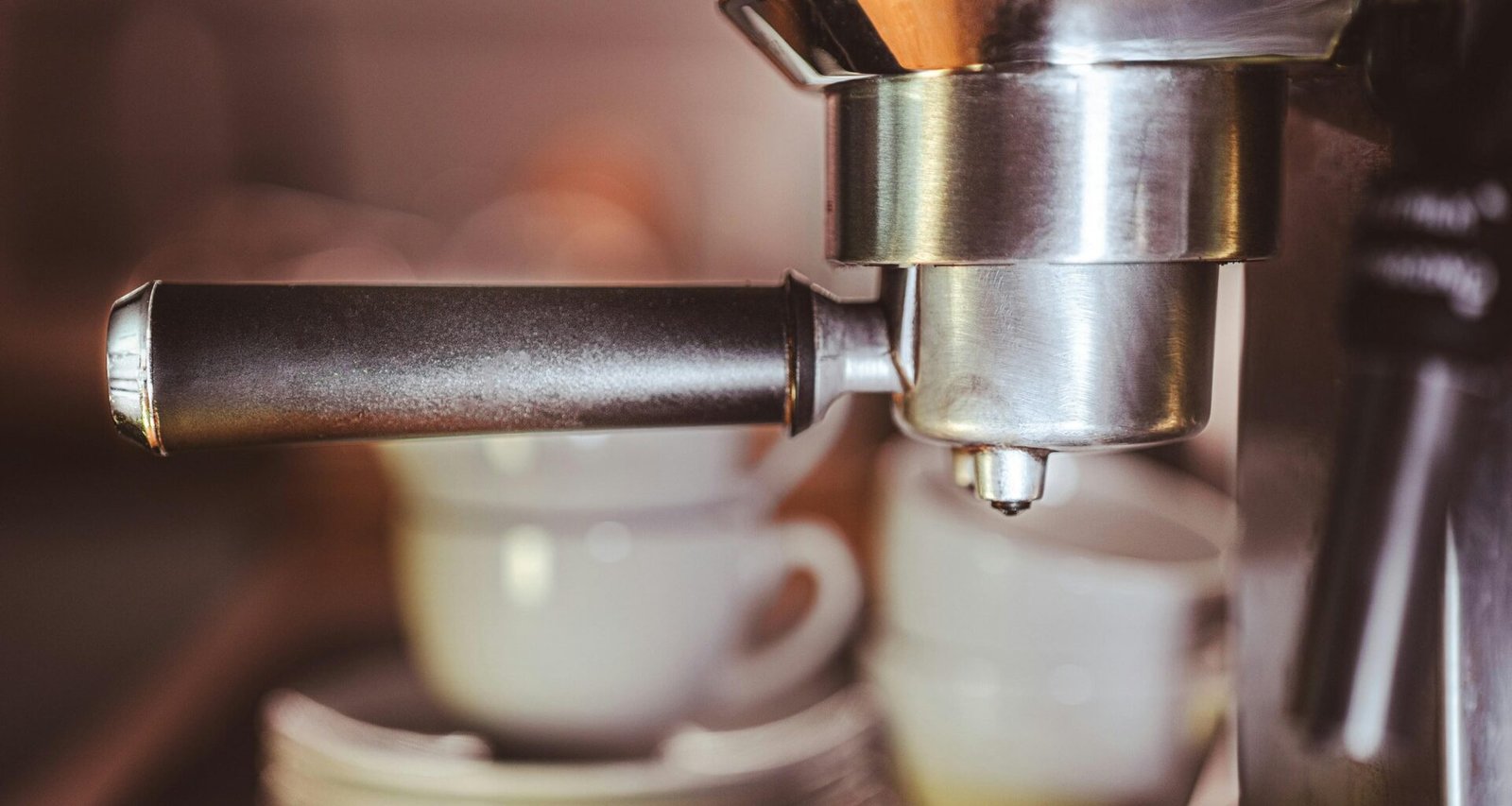 Nahaufnahme einer modernen Kaffeemaschine mit zwei weißen Kaffeetassen auf dem Tropfgitter in einer Küche.