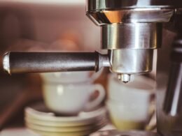 Nahaufnahme einer modernen Kaffeemaschine mit zwei weißen Kaffeetassen auf dem Tropfgitter in einer Küche.