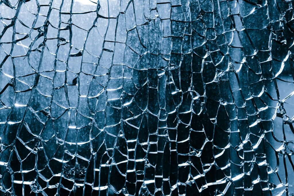 Nahaufnahme von zerbrochenem blauen Glas mit komplexen Rissen und Details in der Struktur.