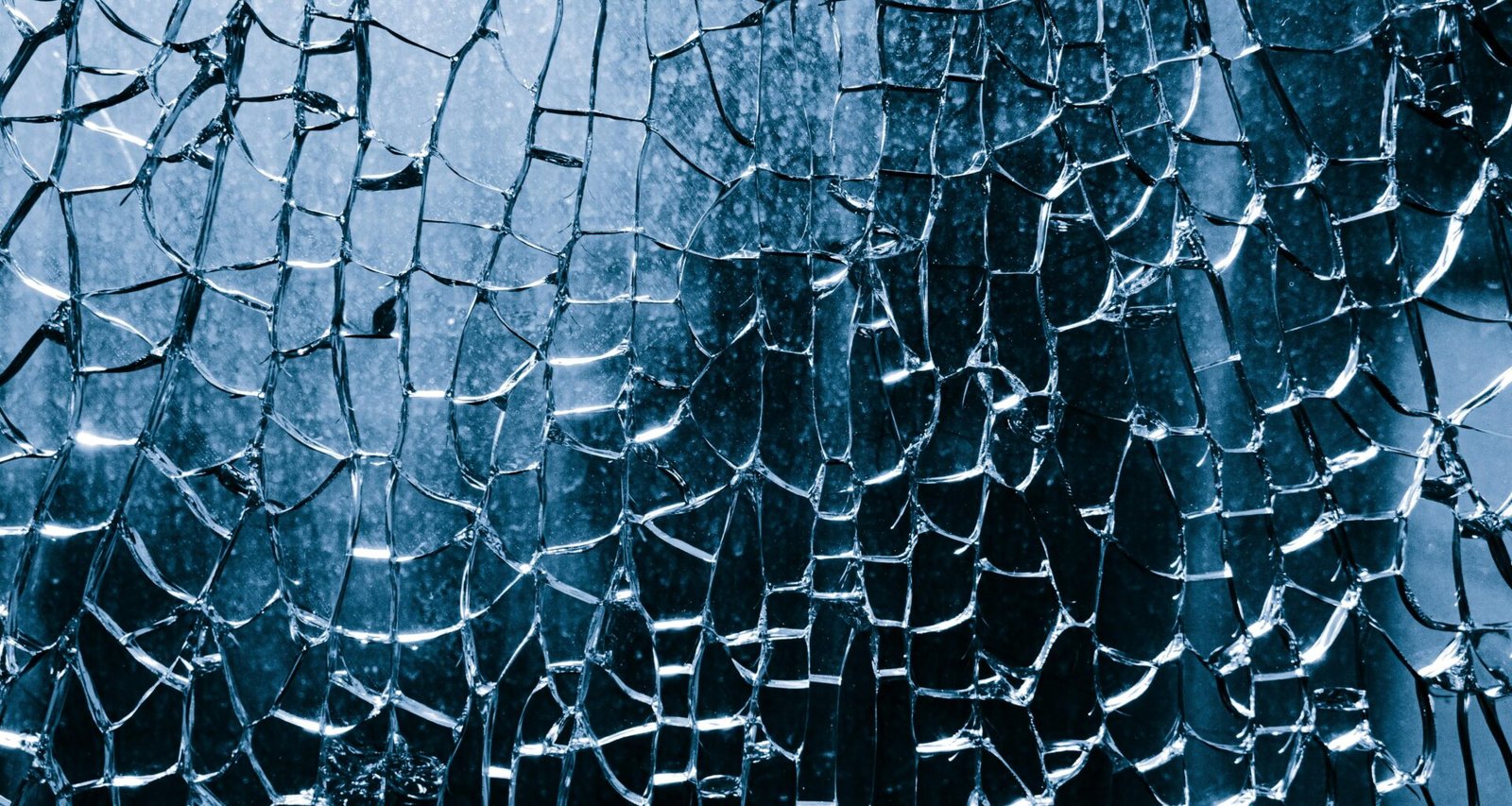 Nahaufnahme von zerbrochenem blauen Glas mit komplexen Rissen und Details in der Struktur.