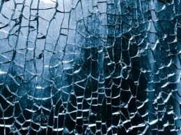 Nahaufnahme von zerbrochenem blauen Glas mit komplexen Rissen und Details in der Struktur.