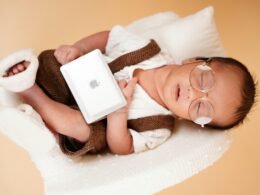 Schlafendes Neugeborenes mit runder Brille, Stirnband und Decke, aufgenommen in sanfter Beleuchtung