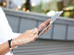 Eine Person hält ein iPad in der Hand, verwendet das Tablet vermutlich zum Arbeiten oder Surfen im Internet.