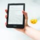 Person hält einen eingeschalteten Amazon Kindle E-Reader in der Hand, geeignet zur Veranschaulichung digitaler Leselösungen