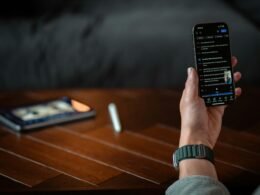 Eine Person hält ein Smartphone mit ausgeschaltetem oder dunklem Bildschirm in der Hand, Fokus auf moderne mobile Technologien.