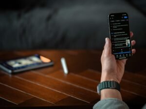 Eine Person hält ein Smartphone mit ausgeschaltetem oder dunklem Bildschirm in der Hand, Fokus auf moderne mobile Technologien.