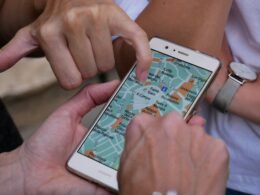Nahaufnahme einer Hand, die ein Smartphone berührt, Symbol für mobile Technologien und digitale Kommunikation.