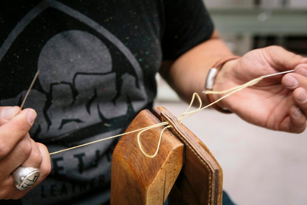 Person im schwarzen T-Shirt hält ein braunes Holz-Plektrum für die Gitarre in der Hand, Fokus auf das Plektrum