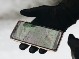 Person hält ein iPhone 6 mit schwarzer Schutzhülle in der Hand, Fokus auf das Smartphone und dessen Nutzung.