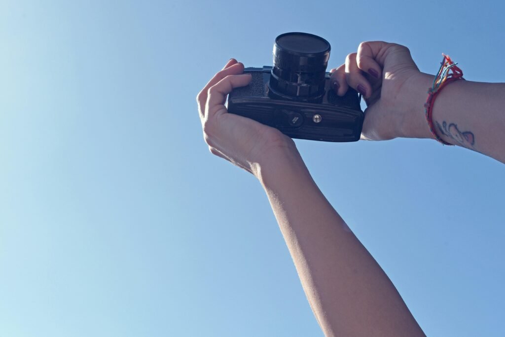 Eine Person hält eine schwarze DSLR-Kamera in der Hand und bereitet sich auf eine Aufnahme vor
