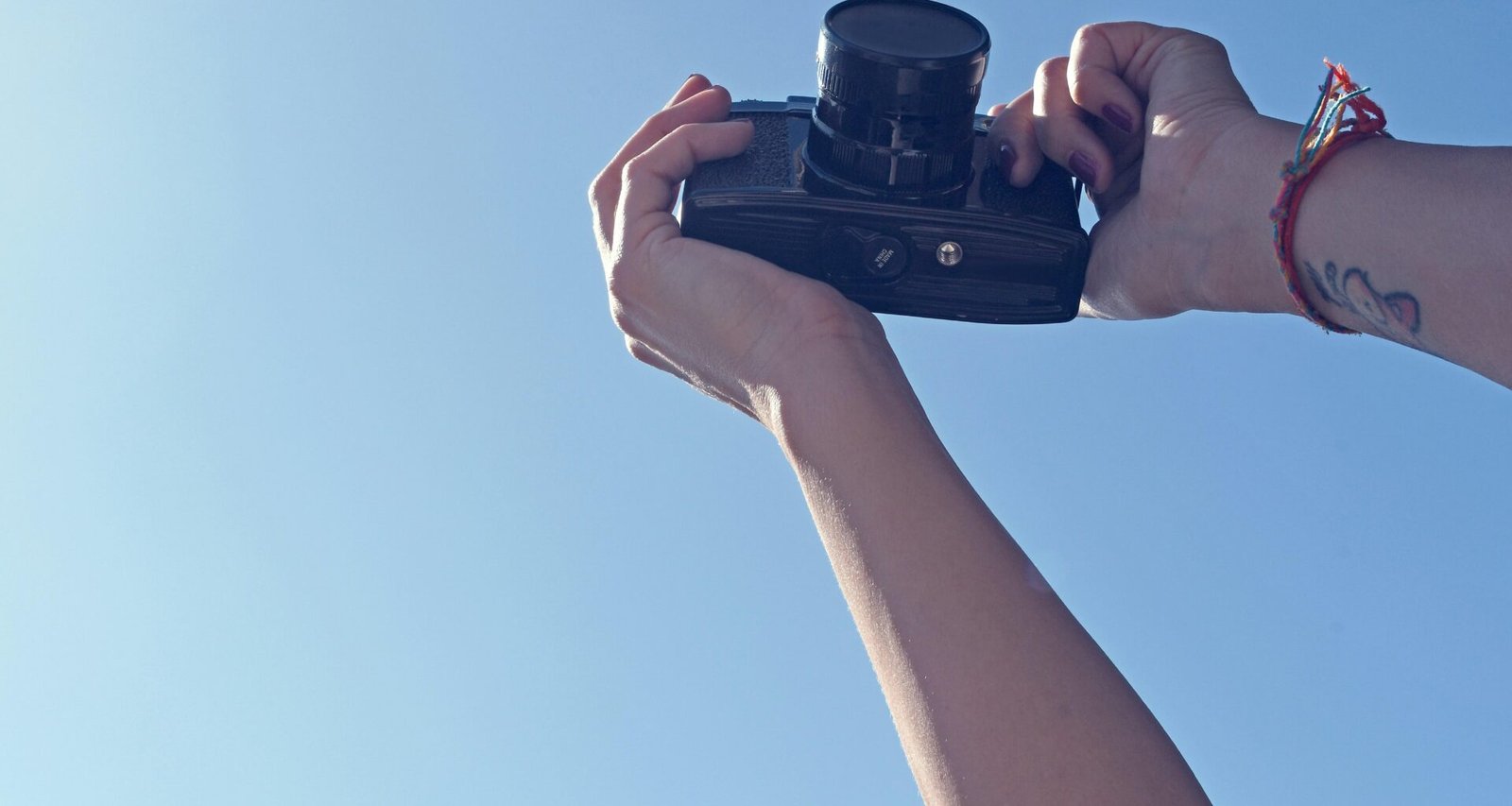 Eine Person hält eine schwarze DSLR-Kamera in der Hand und bereitet sich auf eine Aufnahme vor