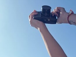 Eine Person hält eine schwarze DSLR-Kamera in der Hand und bereitet sich auf eine Aufnahme vor