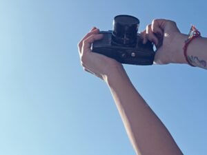 Eine Person hält eine schwarze DSLR-Kamera in der Hand und bereitet sich auf eine Aufnahme vor