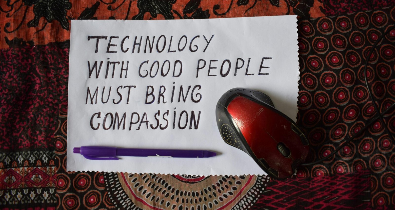 Eine rote und schwarze kabellose Computermaus liegt auf einem hellen Untergrund, modernes Technikzubehör im Fokus