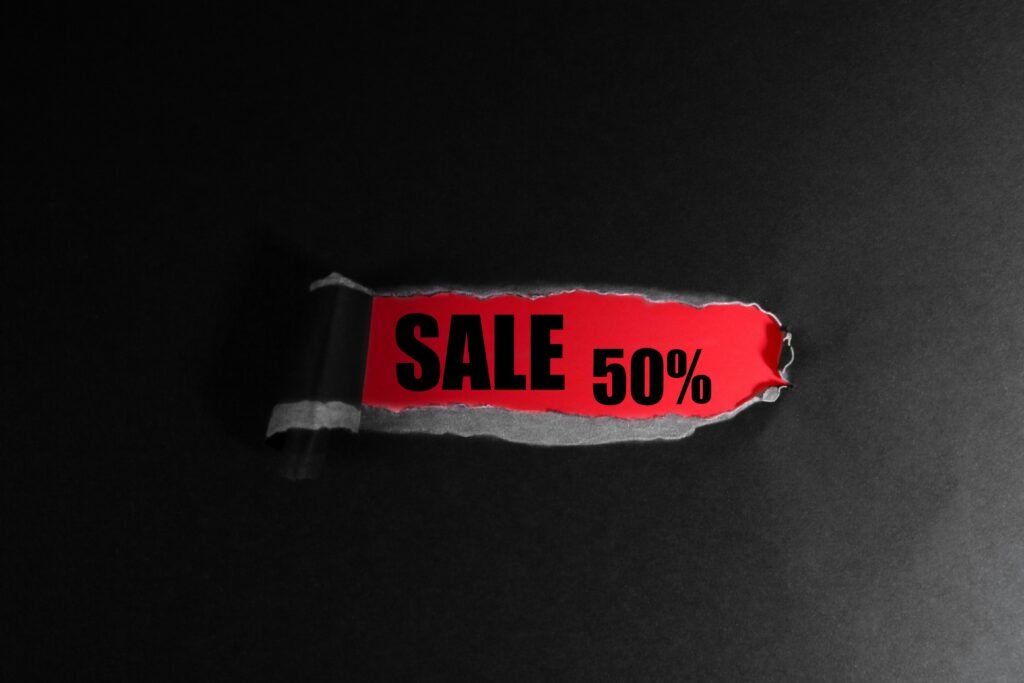 Roter Anhänger mit der Aufschrift 'Sale 50%' auf schwarzem Hintergrund als Symbol für Rabattaktionen im Online-Handel