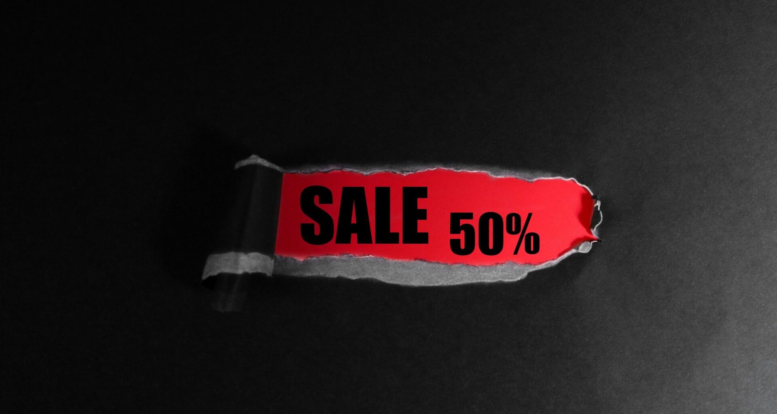 Roter Anhänger mit der Aufschrift 'Sale 50%' auf schwarzem Hintergrund als Symbol für Rabattaktionen im Online-Handel