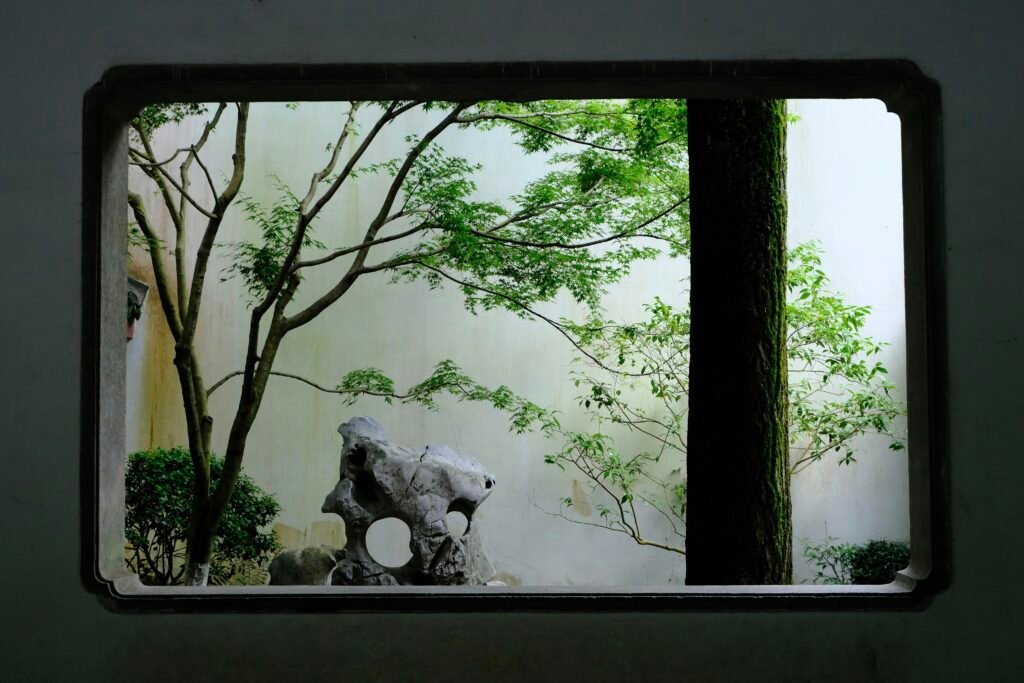 Gartenlandschaft durch ein verziertes Fenster mit klaren Linien und Pflanzen im Hintergrund betrachtet