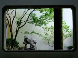 Gartenlandschaft durch ein verziertes Fenster mit klaren Linien und Pflanzen im Hintergrund betrachtet