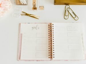 Geöffneter Spiralblock mit Schere und zwei Büroklammern daneben auf einem Schreibtisch, ideales Setup für Büroarbeit oder Planung