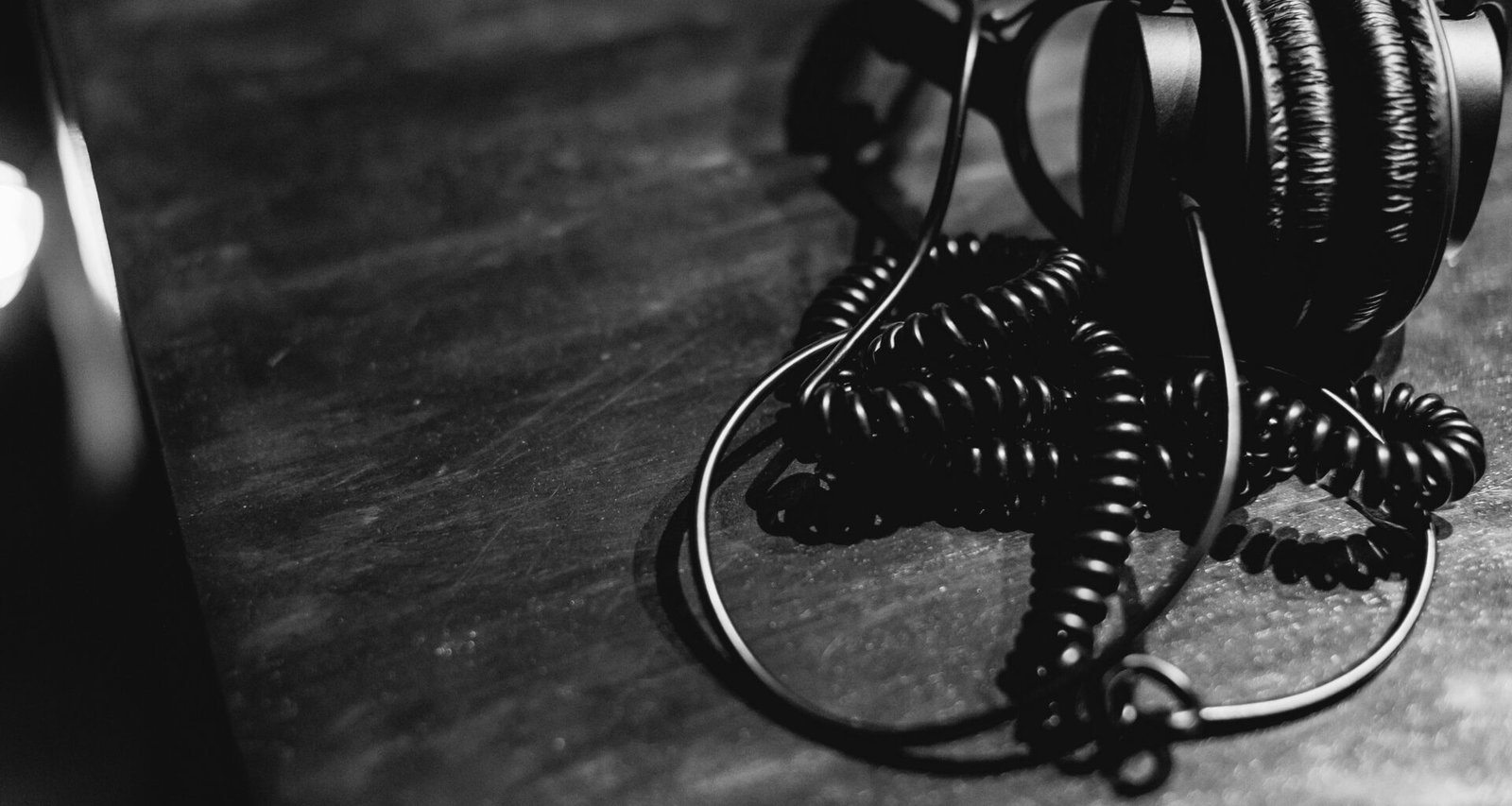 Schwarze und weiße Kopfhörer mit Spiralkabel liegen mittig auf einem Tisch, fotografiert aus der Vogelperspektive.