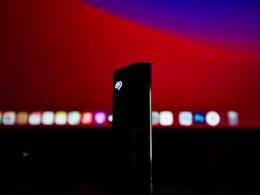 Schwarzes rechteckiges elektronisches Gerät auf leuchtend roter Oberfläche, modernes Technikdesign