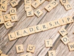 Nahaufnahme von Scrabble-Buchstaben, die auf einer Holzoberfläche das Wort Leadership bilden