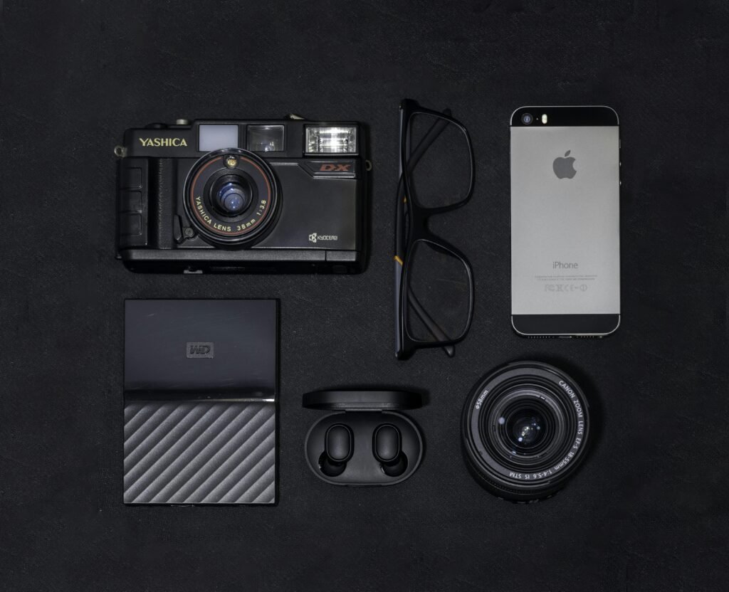 Ein silbernes iPhone 6 liegt neben einer schwarzen und grauen Kamera auf einer ebenen Fläche.