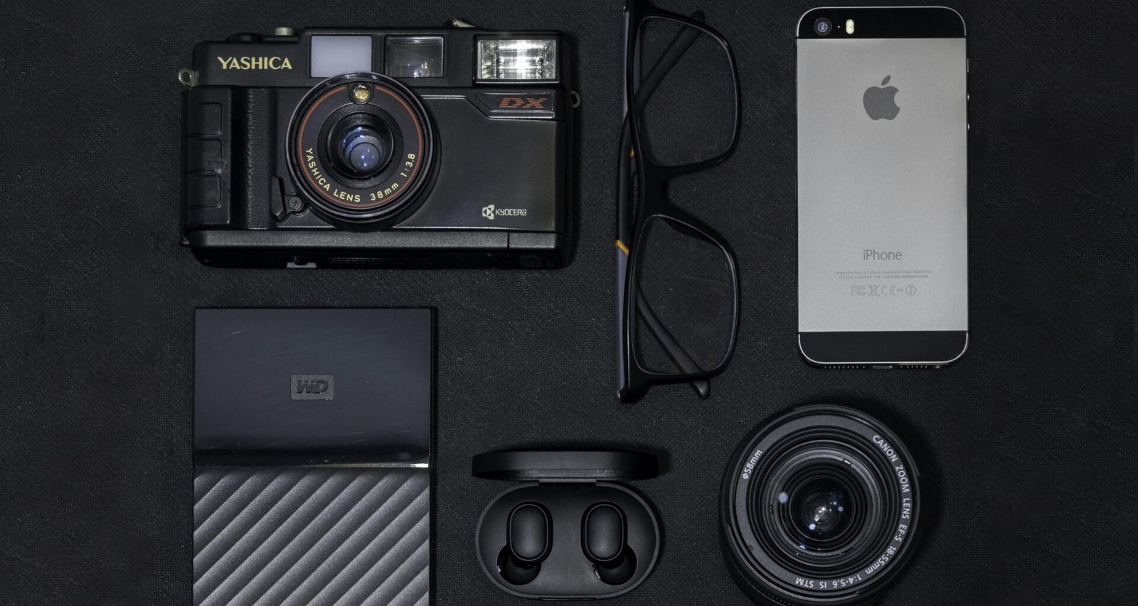 Ein silbernes iPhone 6 liegt neben einer schwarzen und grauen Kamera auf einer ebenen Fläche.