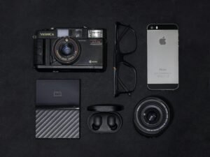 Ein silbernes iPhone 6 liegt neben einer schwarzen und grauen Kamera auf einer ebenen Fläche.