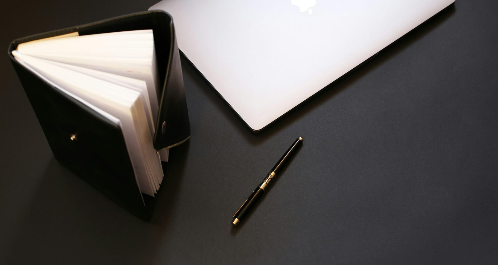 Silbernes MacBook neben einem schwarzen Stift auf einem hellen Schreibtisch als Symbol moderner Arbeitsumgebungen