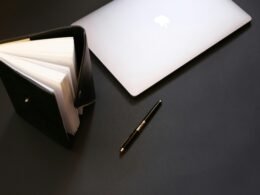 Silbernes MacBook neben einem schwarzen Stift auf einem hellen Schreibtisch als Symbol moderner Arbeitsumgebungen