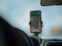 Smartphone mit Navigations-App auf dem Armaturenbrett eines Autos, das eine geplante Route anzeigt, moderne Navigationstechnologie