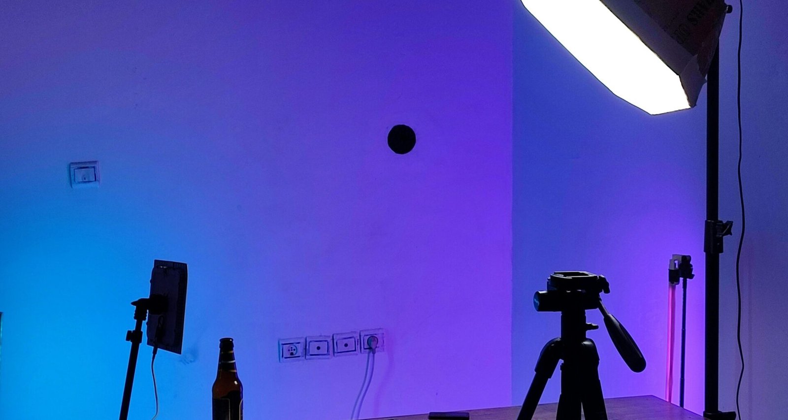 Studioeinrichtung mit professioneller Beleuchtung, Kamera auf Stativ und einem Tisch, ideal für Foto- oder Videoaufnahmen.