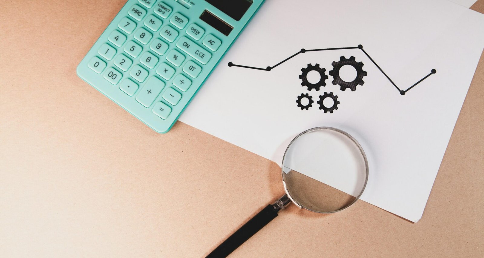 Ein Taschenrechner, eine Lupe und ein Papier mit Diagramm und Zahnrädern zeigen Analyse- und Optimierungsprozesse im Online-Marketing.