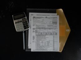 Taschenrechner und Dokumente im Ordner auf einer dunklen Tischoberfläche, arrangiert für effiziente Büroarbeit