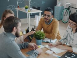 Ein vielfältiges Team arbeitet gemeinsam an einem Schreibtisch in einem modernen Büro und diskutiert Ideen.
