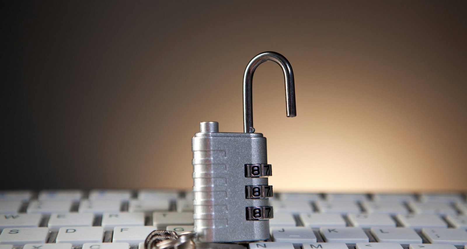 Ein geöffnetes Zahlenschloss mit Zahlenkombination liegt auf einer Computertastatur und symbolisiert Cybersicherheit