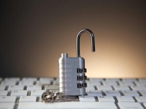 Ein geöffnetes Zahlenschloss mit Zahlenkombination liegt auf einer Computertastatur und symbolisiert Cybersicherheit