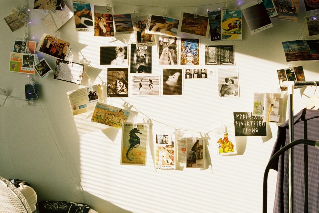 Wand mit Postkarten, aufgehängt an Schnüren und illuminiert durch Lichterketten, als kreative Raumdekoration