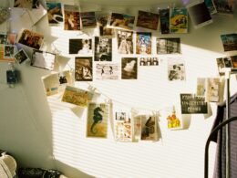 Wand mit Postkarten, aufgehängt an Schnüren und illuminiert durch Lichterketten, als kreative Raumdekoration