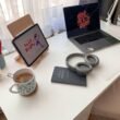 Weiße und blaue Keramiktasse neben einem schwarzen Laptop auf einem weißen Arbeitstisch im modernen Büro