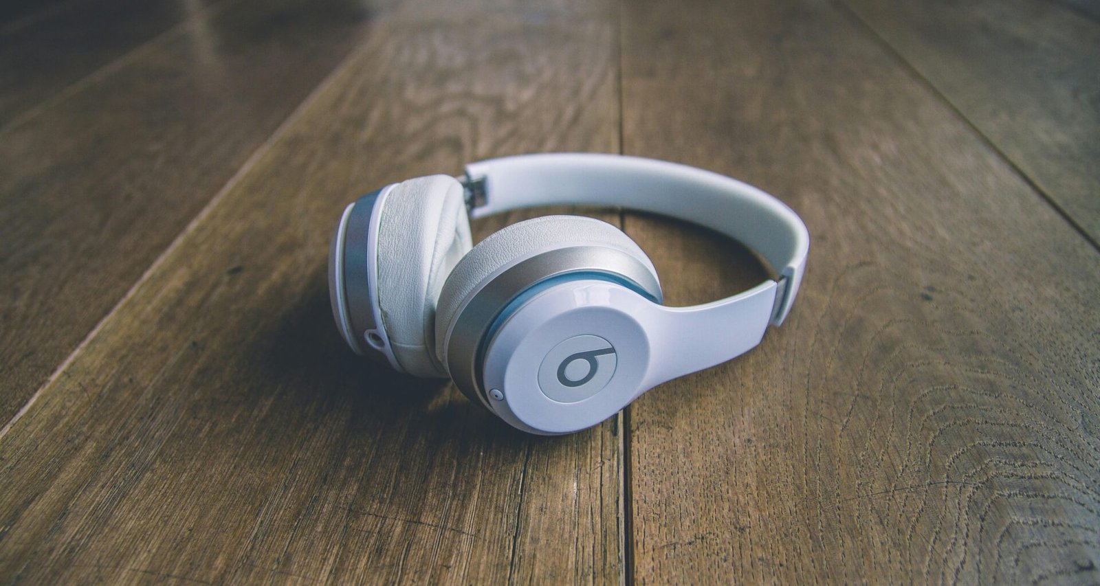 Weiße kabellose Beats by Dr. Dre Kopfhörer liegen auf einem schlichten Untergrund, Nahaufnahme der modernen Kopfhörer